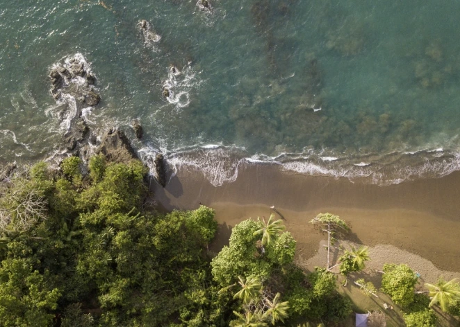 Iguana Divers boat on calm Pacific ocean off Santa Teresa coast with green jungle hills background